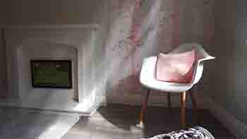 Fireplace and corner chair in dappled sunlight